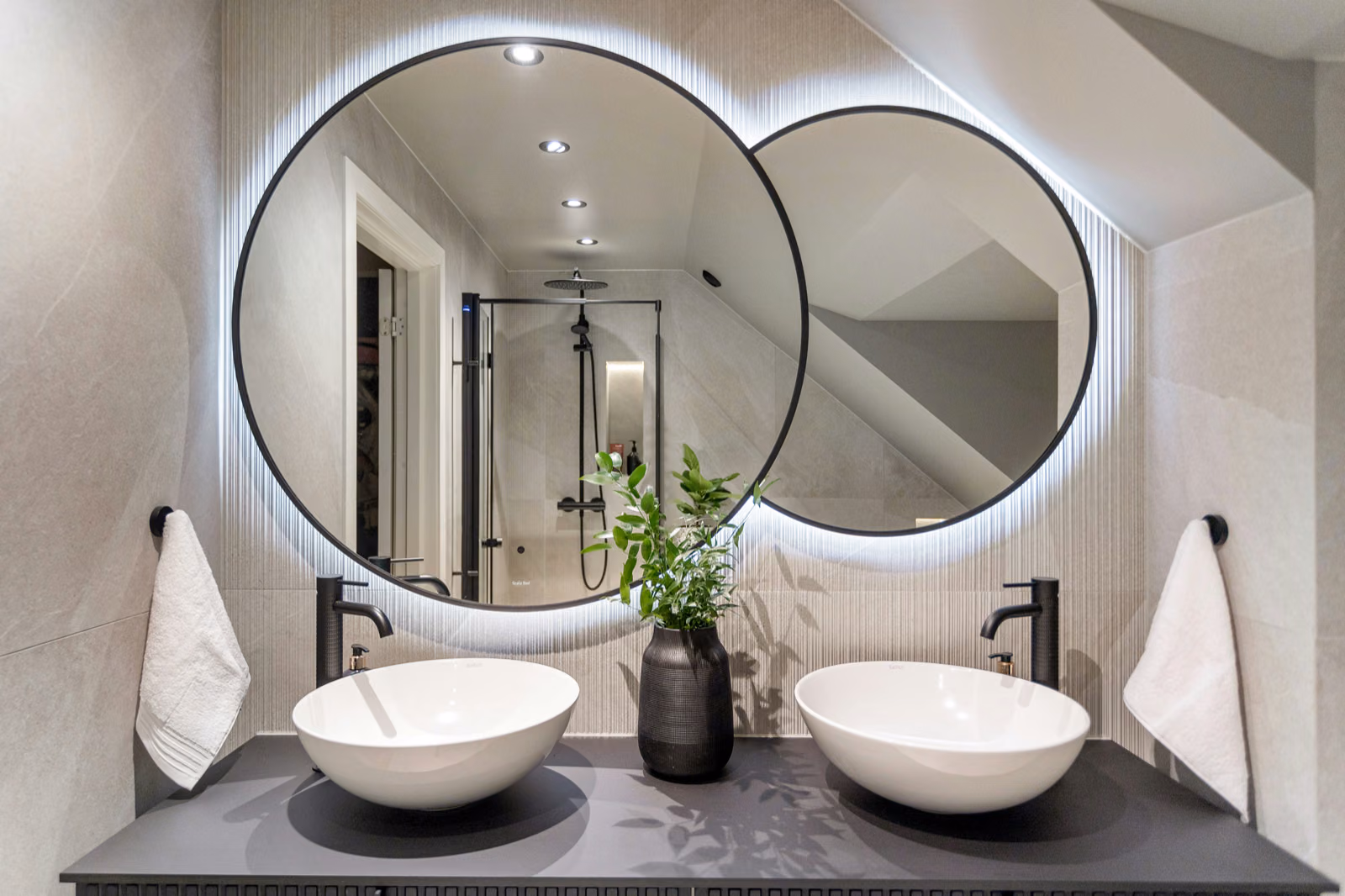 A cozy, well-lit bathroom with multiple Renotive mirrors of varying sizes and shapes artfully arranged on the walls, creating the illusion of depth and space.