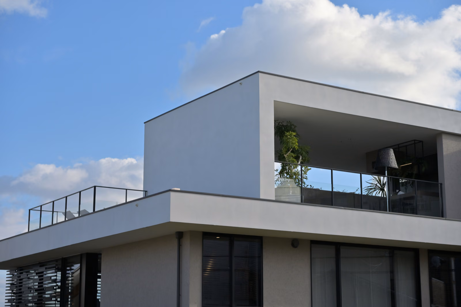 A striking exterior of a modern two-story house with a new sleek roofline, clean lines, and expansive windows that flood the interiors with natural light. The facade features a mix of natural materials like stone and wood, creating a warm, inviting atmosphere. The front yard is meticulously landscaped with lush greenery, complemented by a paved driveway leading to a detached garage. The lighting is designed to showcase the architectural details, casting a warm glow on the home's exterior in the evening. This Renotive-designed home renovation showcases the perfect balance of style and functionality, elevating the overall curb appeal and increasing the home's value.