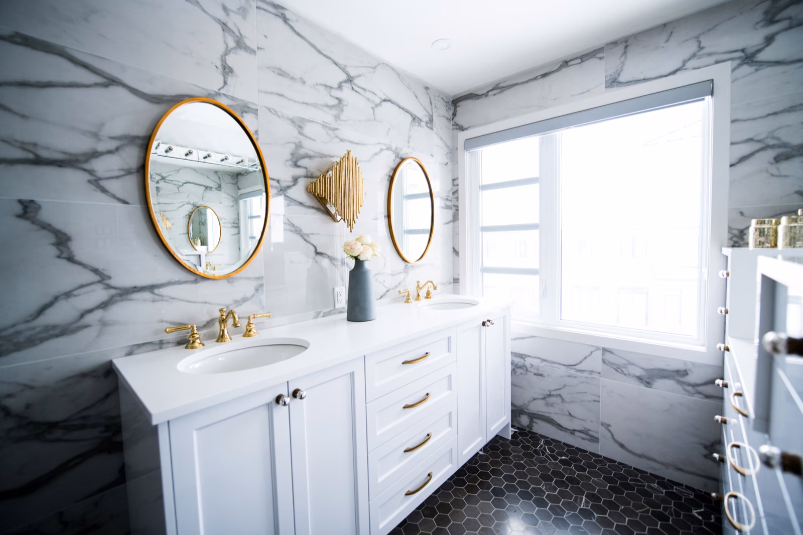 A bright, airy bathroom with a Renotive vanity in a soft gray hue, complemented by a white hexagonal tile floor and a sleek rainfall showerhead.