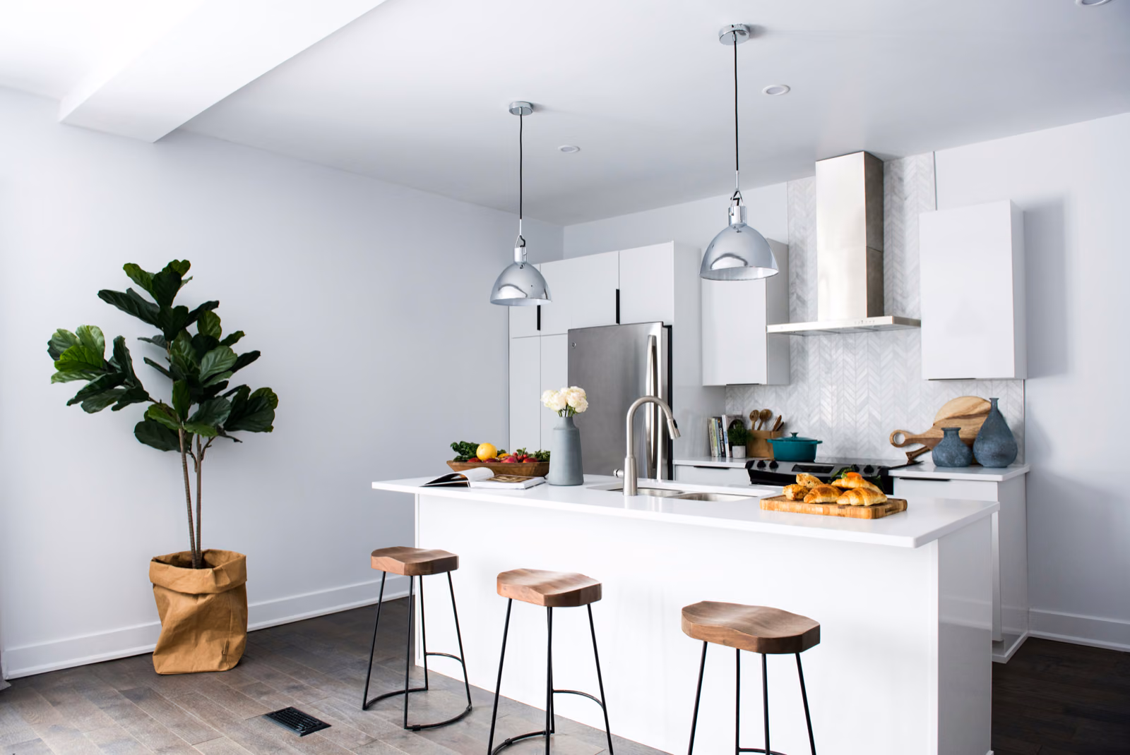 A bright, sunlit interior featuring a Renotive kitchen remodel. In the foreground, sleek white cabinets and stainless steel appliances gleam.