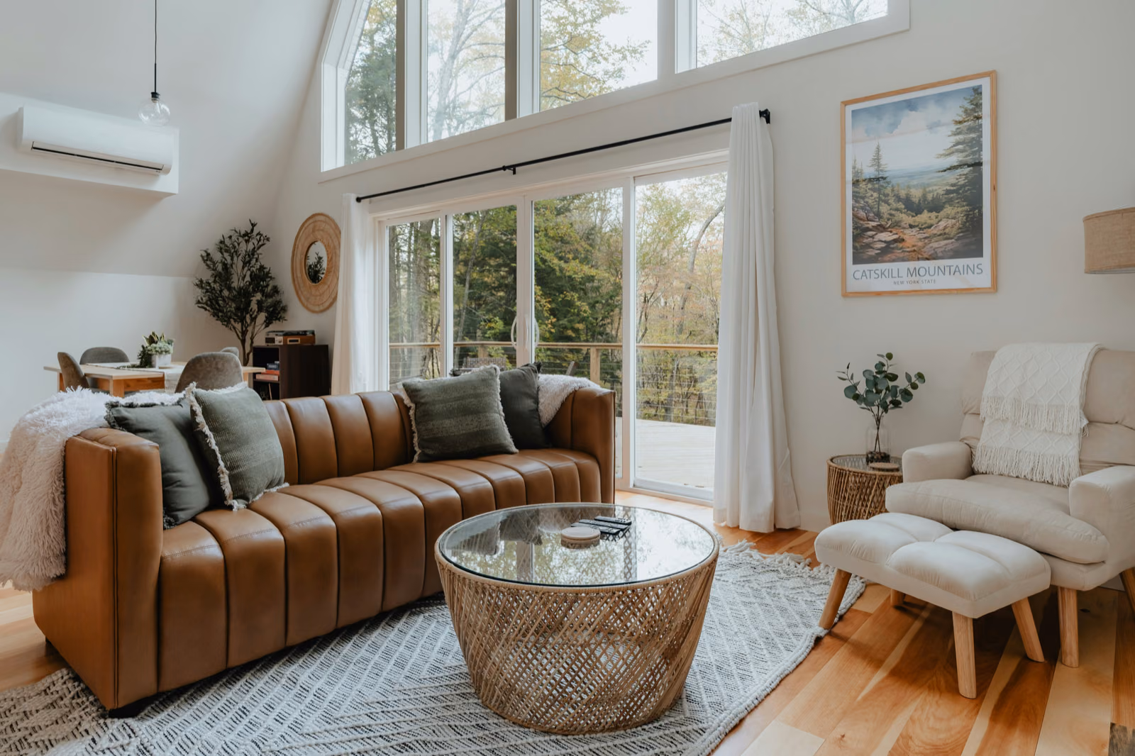 A bright, airy living room with large windows that let in natural light. The walls are painted a soothing shade of white, and the floors are a warm hardwood.