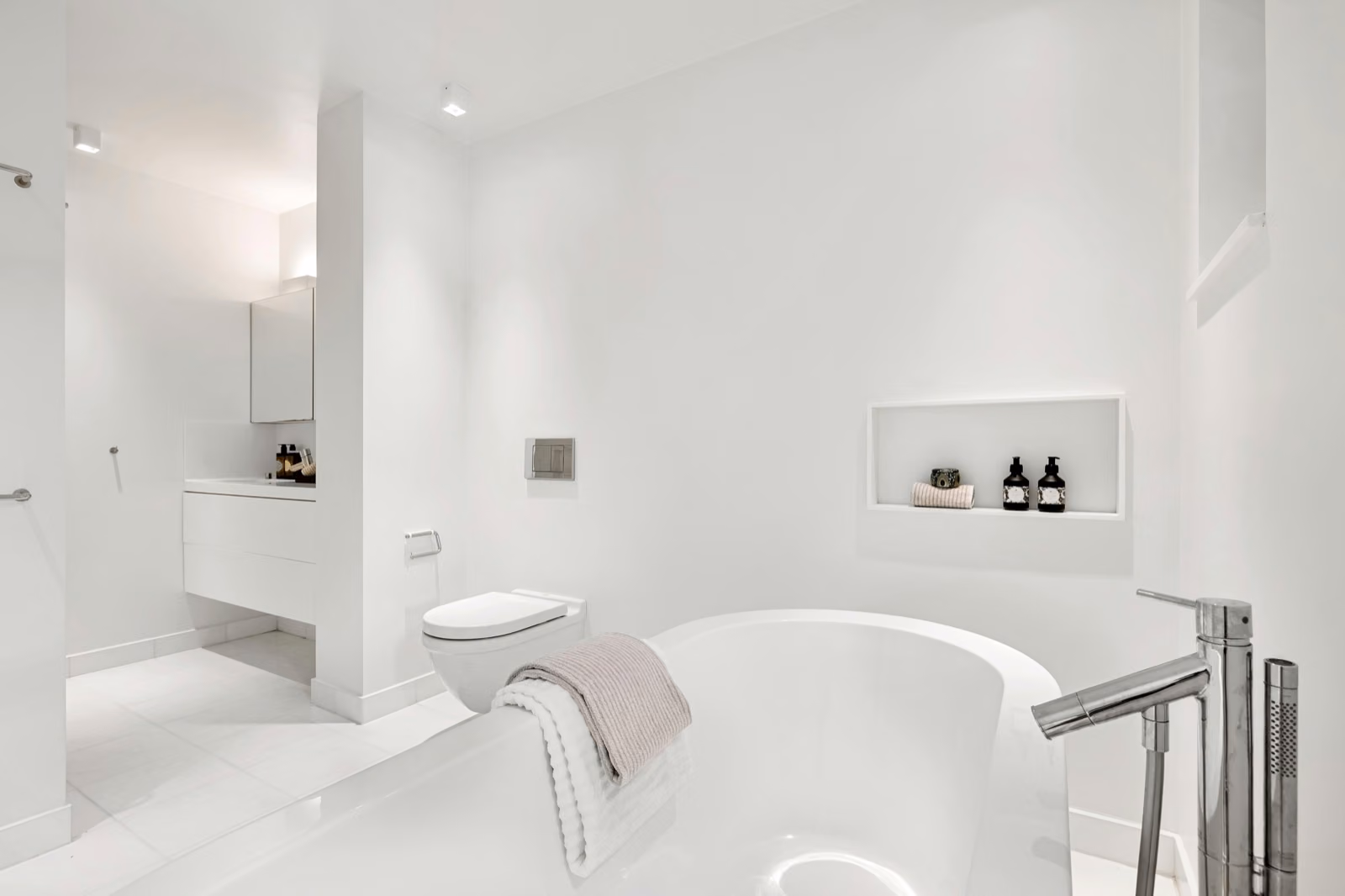 A bright, modern bathroom with a sleek, one-day remodeled Renotive bathtub as the focal point. The tub is surrounded by gleaming white subway tiles, with a large window letting in natural light. In the foreground, a variety of brushes, caulk, and other tools are neatly arranged, indicating the recent completion of the project. The middle ground features a partially completed caulking job, highlighting the seamless integration of the new tub. In the background, a minimalist vanity and mirror create a clean, spa-like atmosphere.