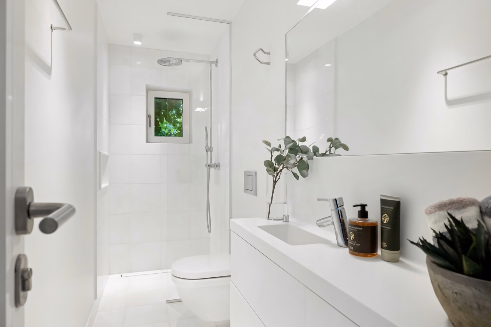 A bright, modern bathroom with sleek, white tiles and a stylish vanity.