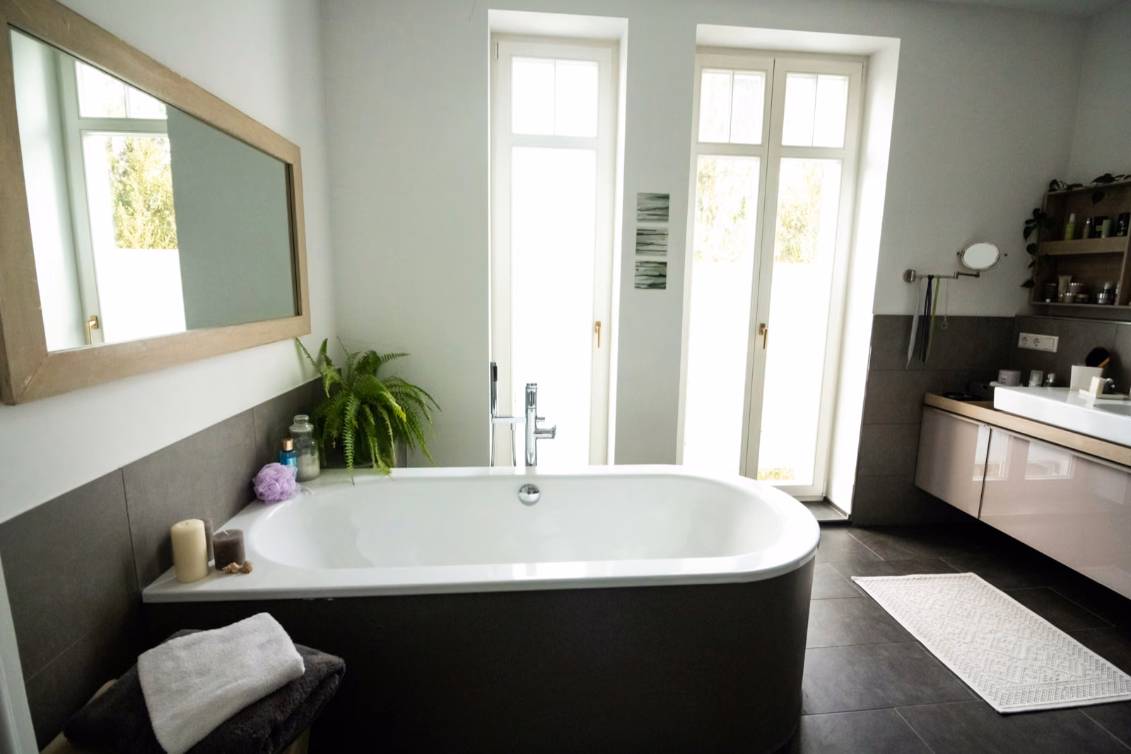 A bright, minimalist bathroom interior with crisp white tiles and clean lines. The foreground features a range of Renotive tiles in various cost-effective patterns - subway, hexagon, and mosaic - showcasing their versatili